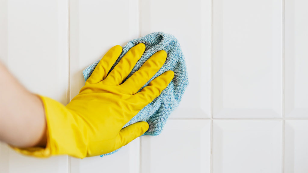 Käsi pyyhkii mikrokuituliinalla laattapintaa