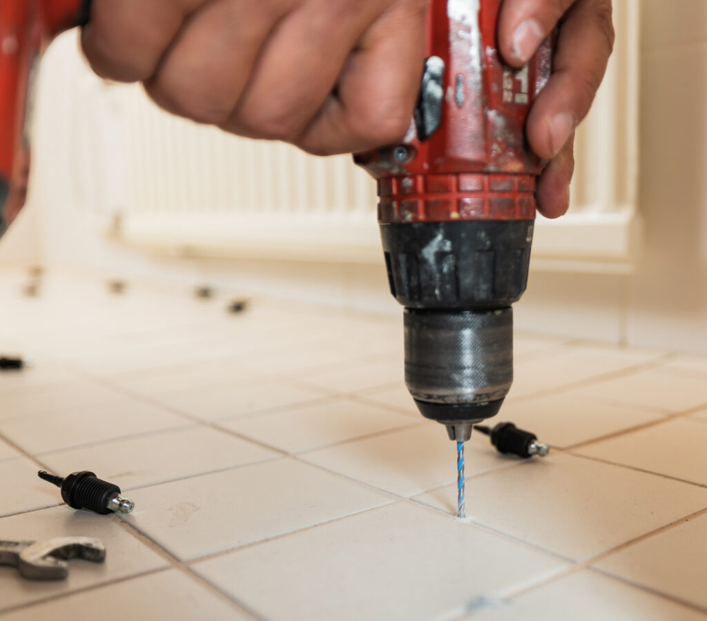 Kylpyhuoneen laattojen väliin porataan pieniä reikiä laattojen injektointia varten